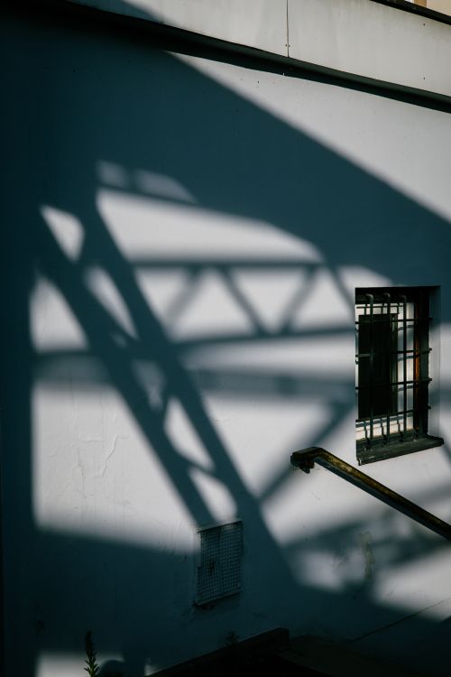Free Shadows of a bridge structure cast on a white wall with a window reflecting architectural design. Stock Photo
