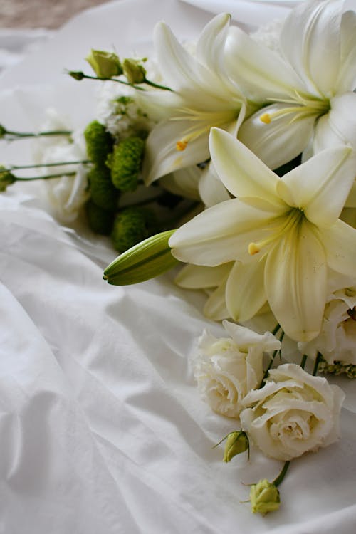 Bouquet of Fresh White Easter Lilies and Roses Lying on a White Fabric