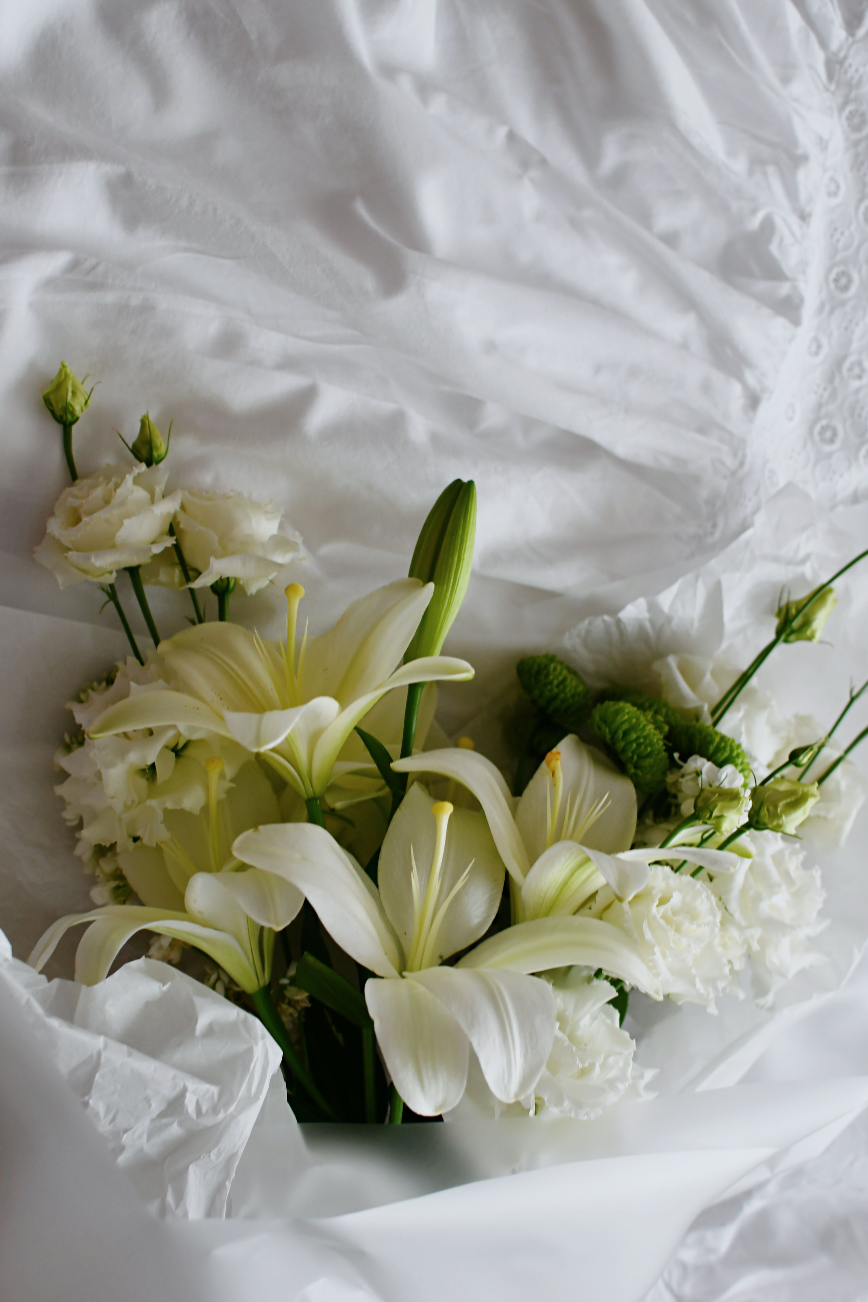 Beautiful white flower bouquet displayed on gentle white fabric, perfect for weddings.