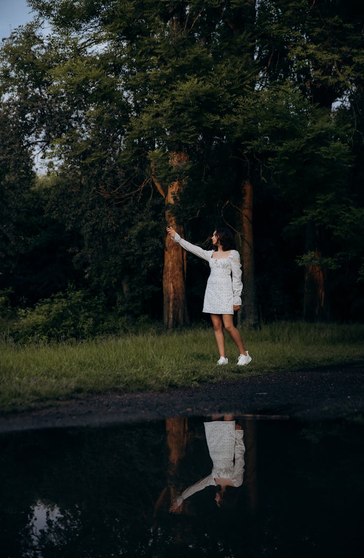 Woman In White Dress Standing On The Grass In A Park