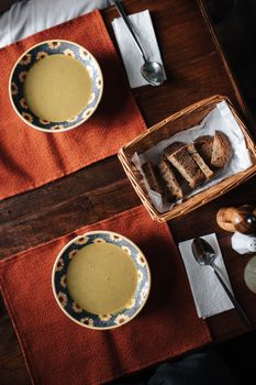 A cozy meal with warm soup and rustic bread on a wooden table, perfect for a comforting dinner.