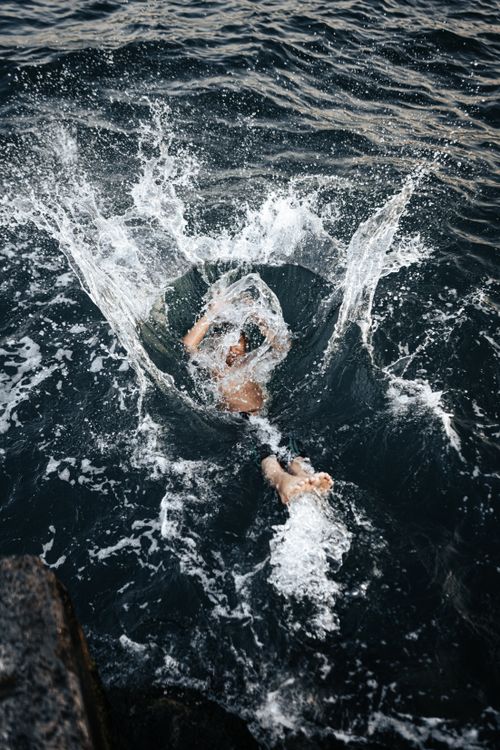 Free A person diving into the sea, captured from above, surrounded by splashes of water. Stock Photo