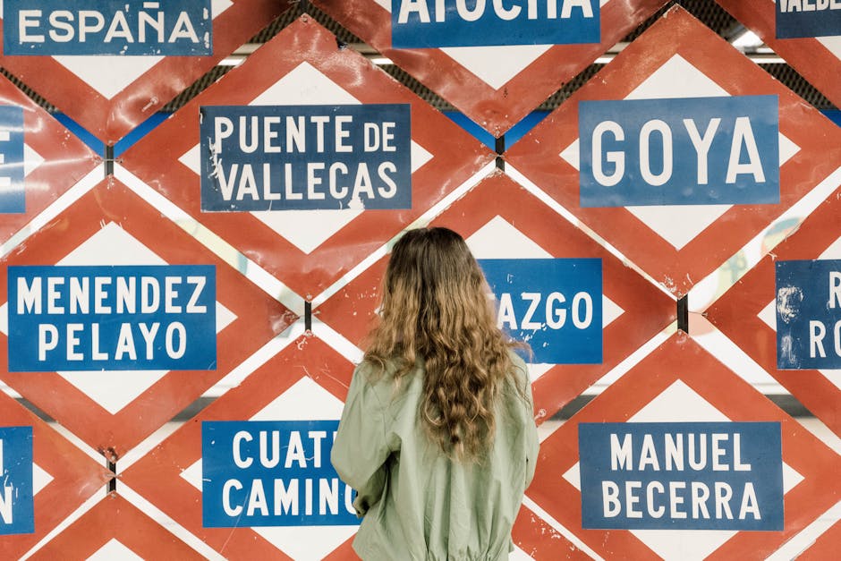 A woman observing multiple metro station signs in Madrid, Spain, showcasing urban exploration.