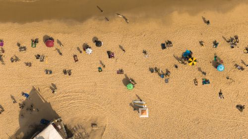 Free Aerial shot of a Rio de Janeiro beach showcasing sunbathers and colorful umbrellas in the sand. Stock Photo