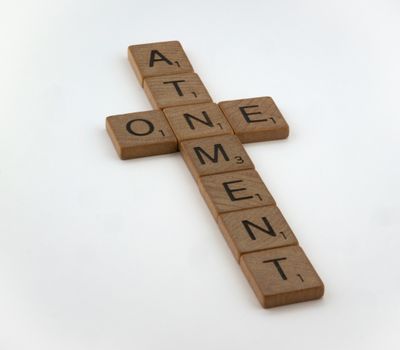 A cross made out of scrabble letters that says atonement