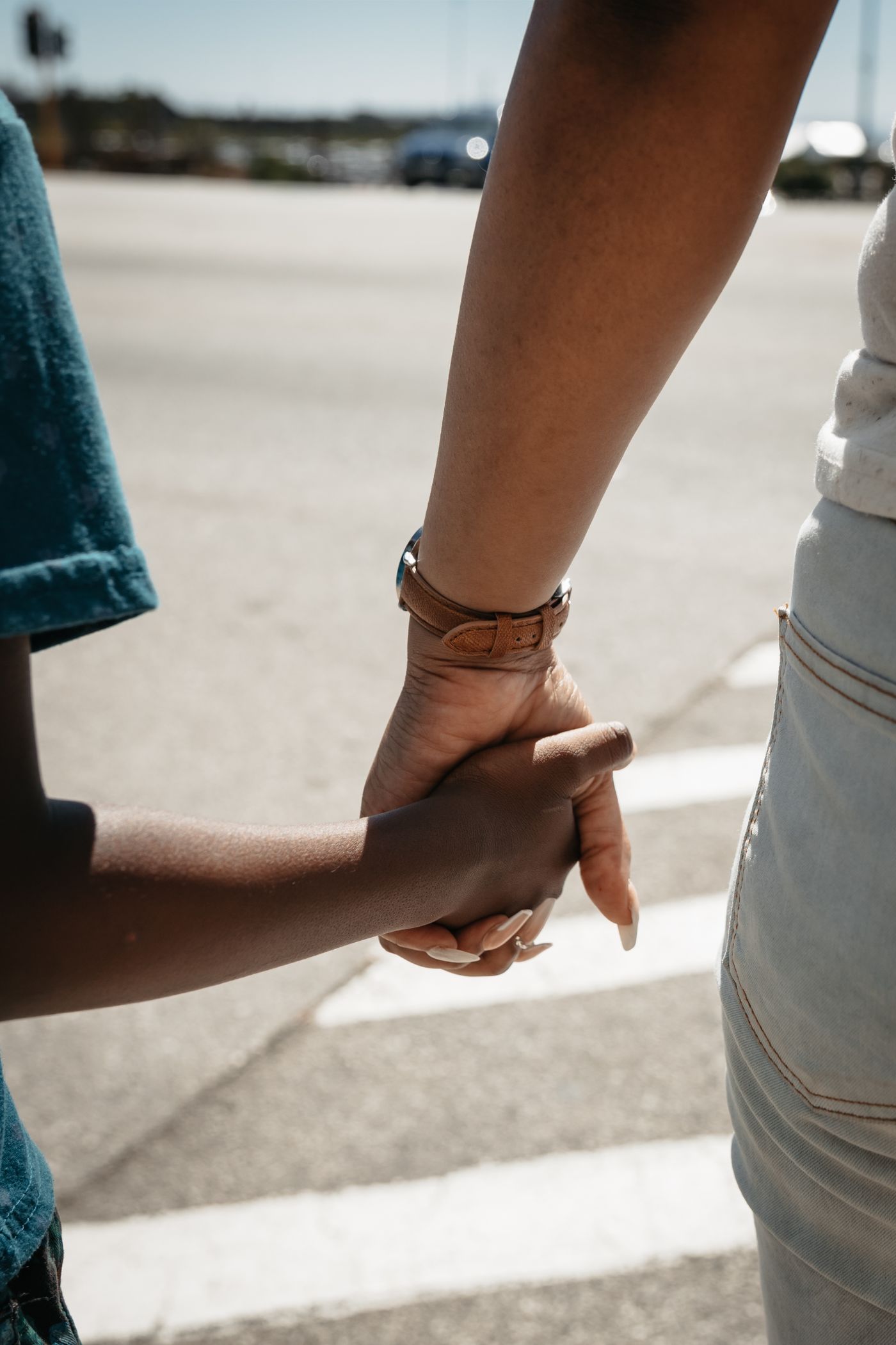 A parent and child crossing a street together; illustrative stock photograph