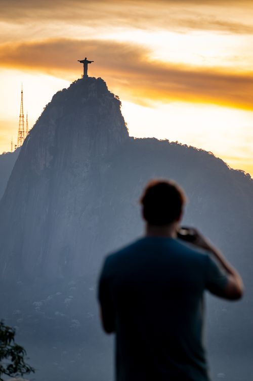 Free A person viewing Christ the Redeemer statue with vibrant sunset skies in Rio de Janeiro, Brazil. Stock Photo