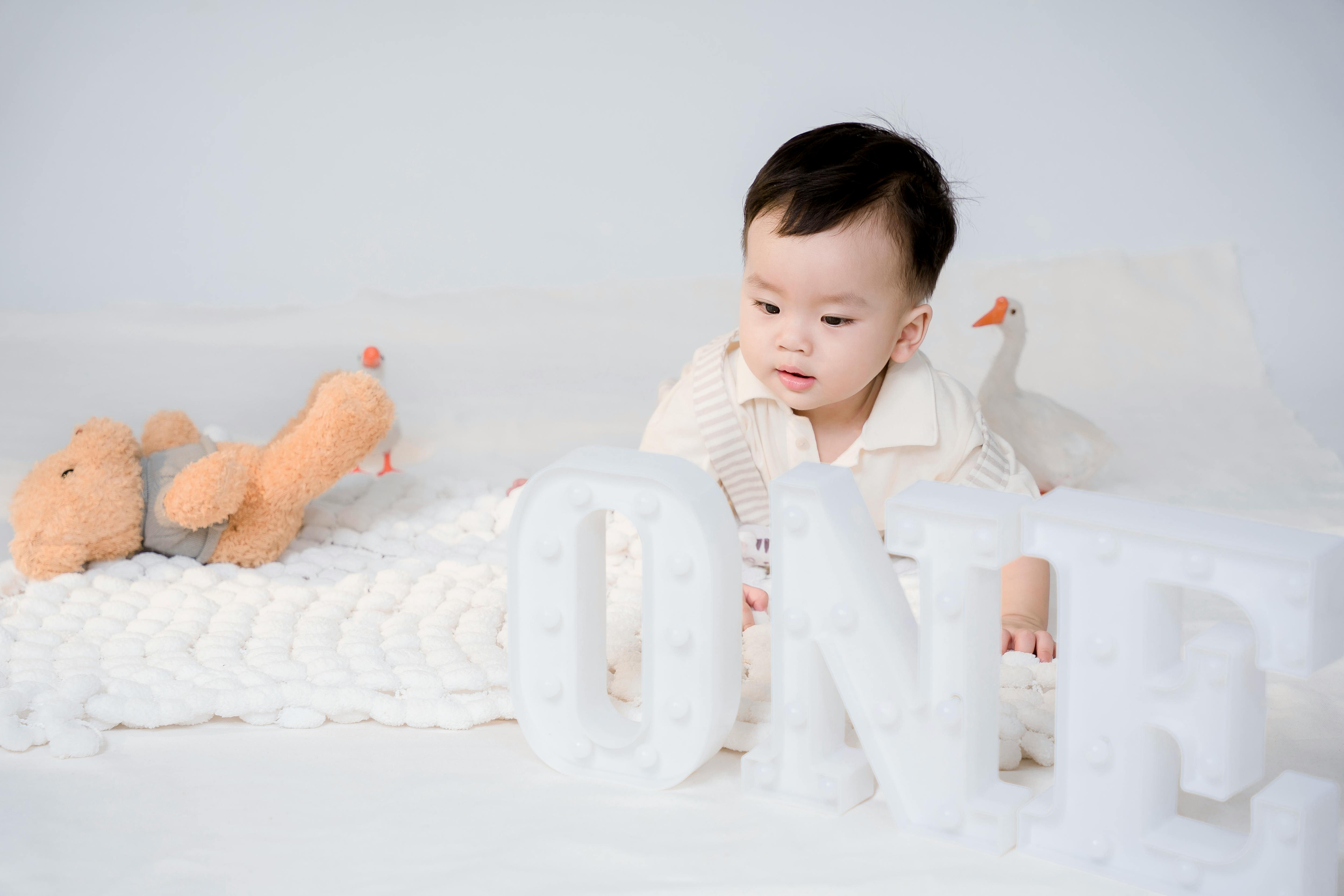 Cute baby with number one sign in a cozy studio photoshoot, perfect for first birthday themes.
