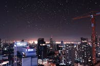 夜幕下，城市的天际线令人惊叹，发光的建筑、星星和起重机点缀其间