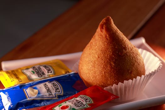 Delicious Brazilian coxinha served with mustard, mayonnaise, and ketchup packets.