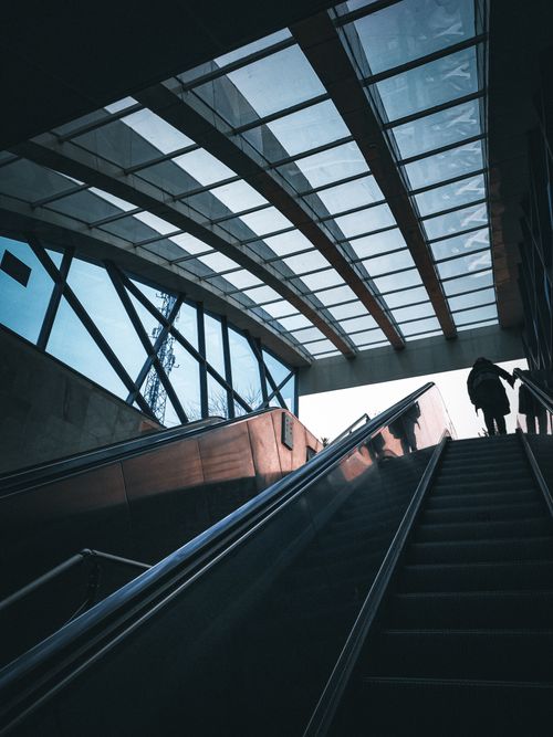 Free A person ascends an escalator in a modern subway station with glass roofing. Stock Photo