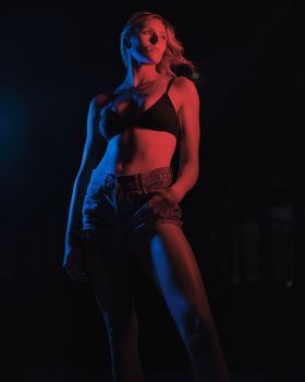 Artistic studio shot of a woman posing under dramatic red and blue lighting, highlighting contours.