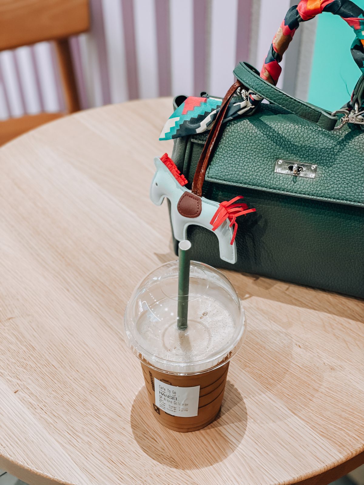 Iced coffee in a plastic cup with a straw next to a bag on a café table