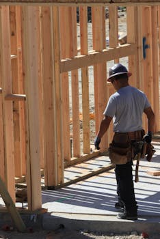 Construction worker on site building wooden frame home during the day.