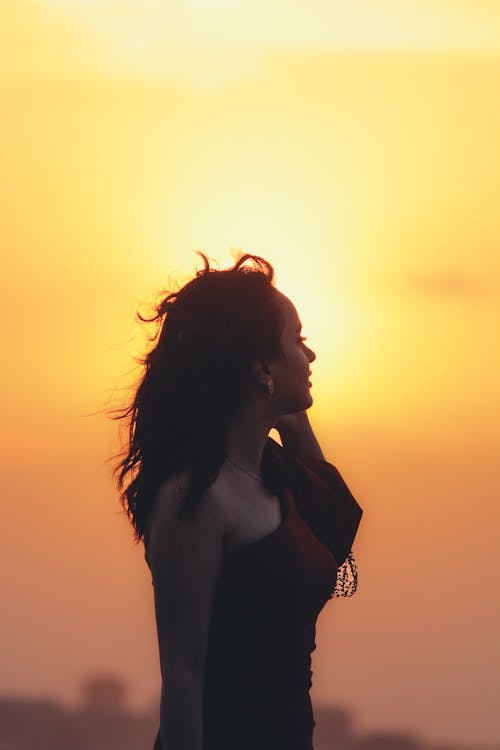 Young Woman Standing against the Setting Sun