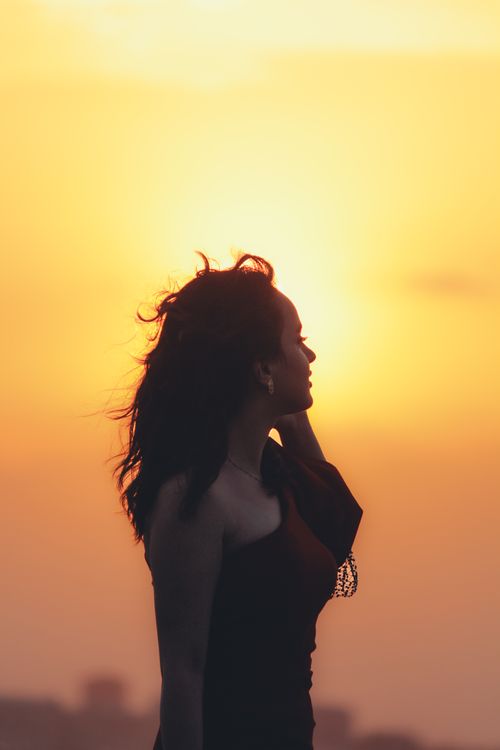 Free A woman in a red dress standing outdoors during sunset, perfect for fashion and lifestyle themes. Stock Photo