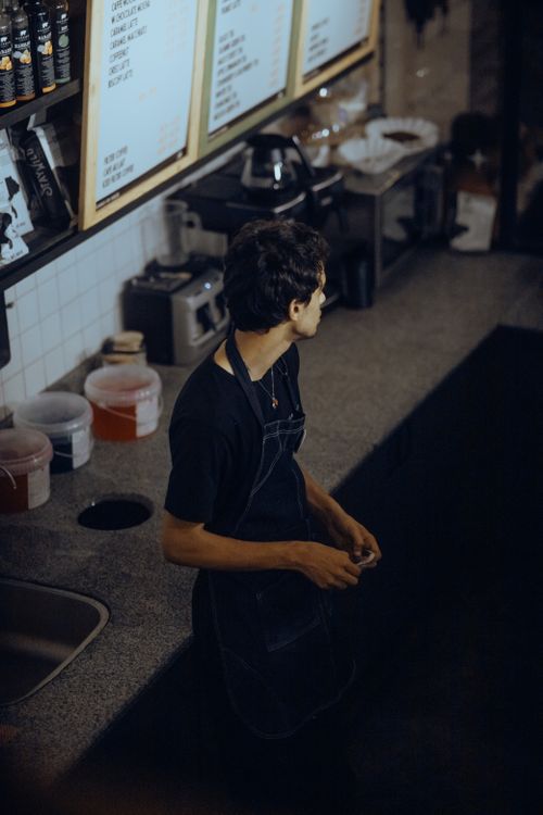 Free A barista in a dark apron standing in a coffee shop captured from above. Stock Photo