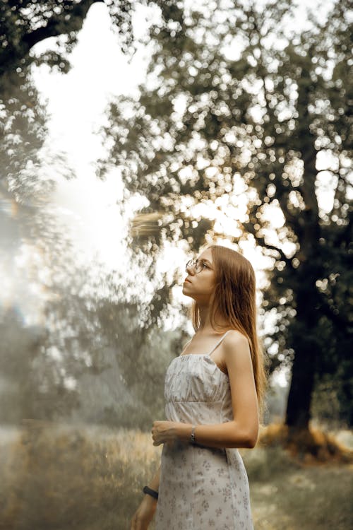 Young Woman in a Dress Standing on a Field in the Forest 