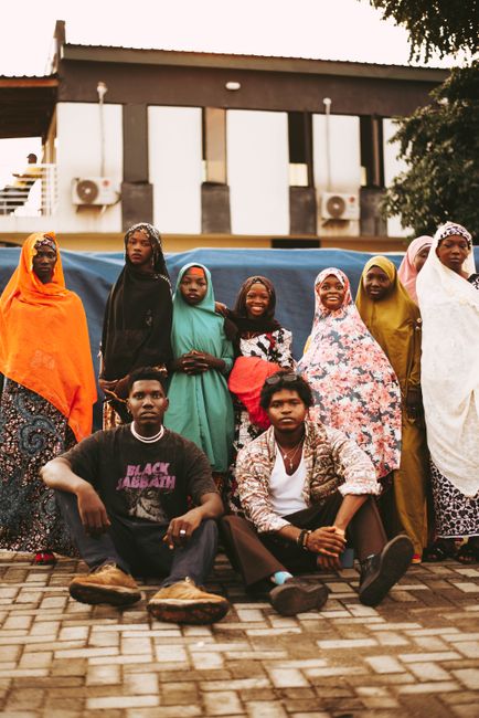 A group of men and women in traditional clothing smiling and posing outdoors.