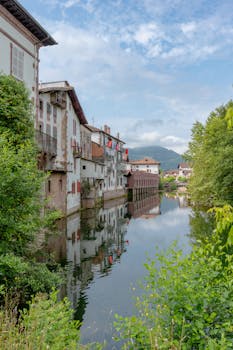Scenic view of traditional buildings by the river in Elizondo, Spain on a sunny day.