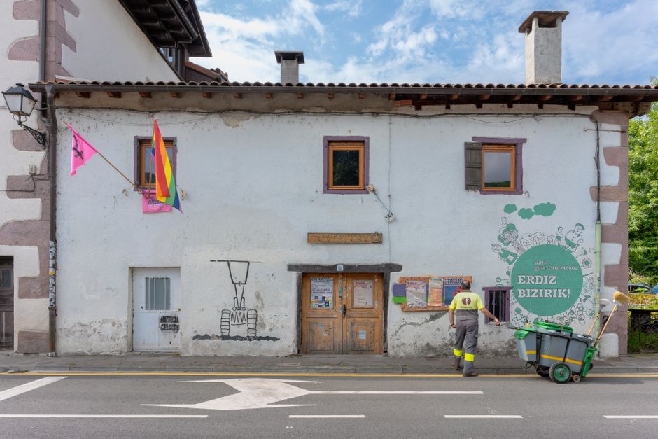 Un limpiador trabaja frente a un edificio cubierto de murales en Elizondo, España.