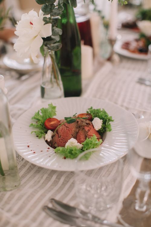 Free Elegant table setting featuring a gourmet dish with salad and floral decor. Stock Photo