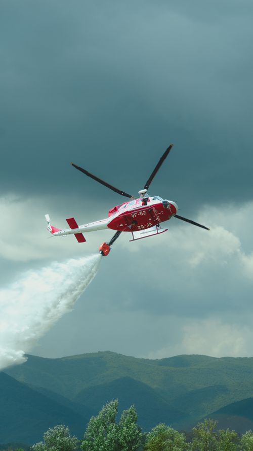 Free Aerial view of a firefighting helicopter dropping water over a forest in Abruzzo, Italia. Stock Photo
