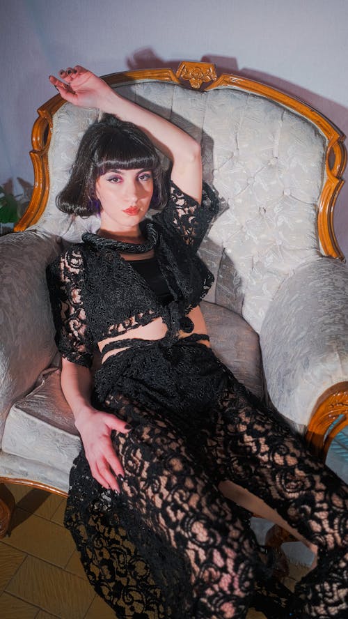 Woman in a Lace Outfit Sitting and Posing on a Sofa