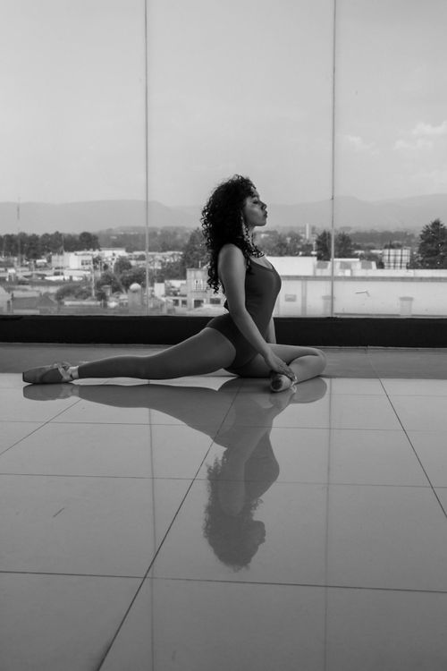 Free Black and white photo of a ballerina practicing indoors with a cityscape view. Stock Photo