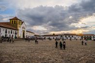 Historic Villa de Leyva square with people enjoying a beautiful sunset and colonial architecture.
