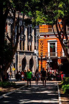 Vibrant street in Puebla, Mexico featuring colonial architecture and people strolling.
