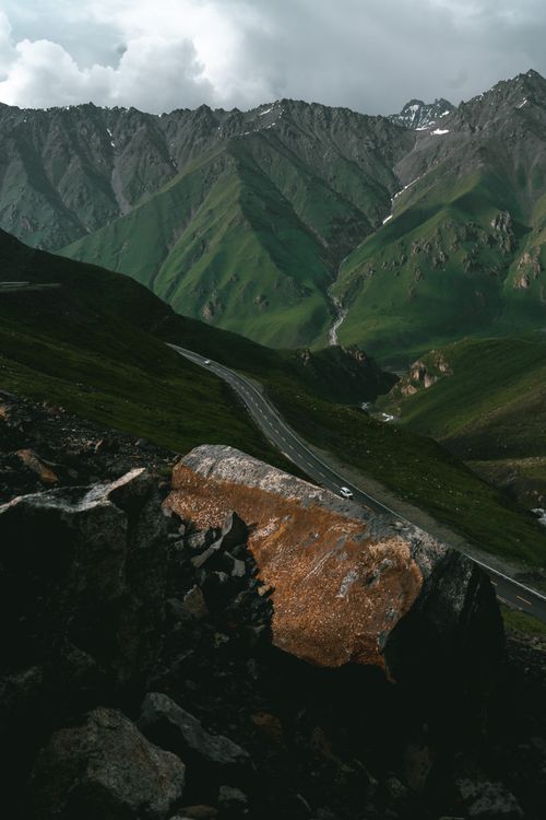 Free Breathtaking aerial view of a winding road through lush green mountains. Perfect for backgrounds. Stock Photo
