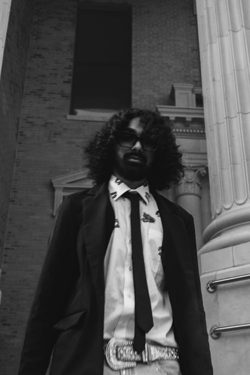 Bearded Man in Black Blazer and Tie Posing by a Column