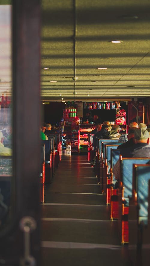 People Sitting on Rows of Seats at a Railway Station Lounge with a Cafeteria