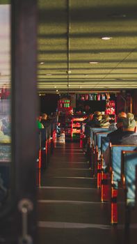 A bustling train lounge with people sitting and rows of seats, creating a warm atmosphere.