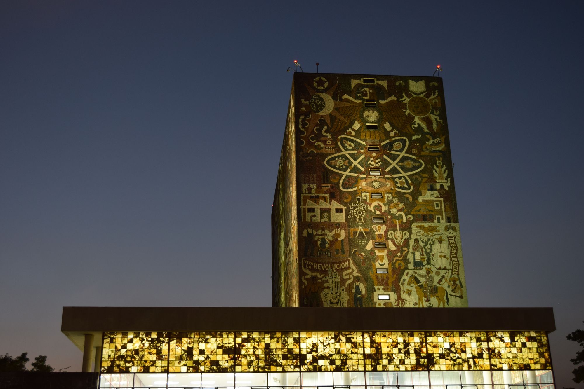 Dusk view of the Biblioteca Central's vibrant mural in Mexico City's UNAM campus.