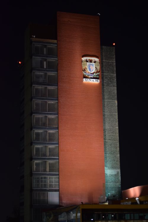 Free Illuminated facade of UNAM building at night in Mexico City, showcasing architectural design and emblem. Stock Photo
