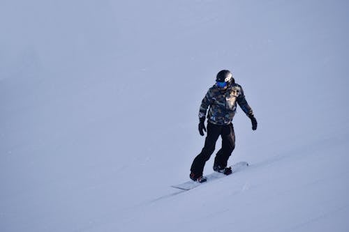 Фотография человека, катающегося на сноуборде на заснеженном поле