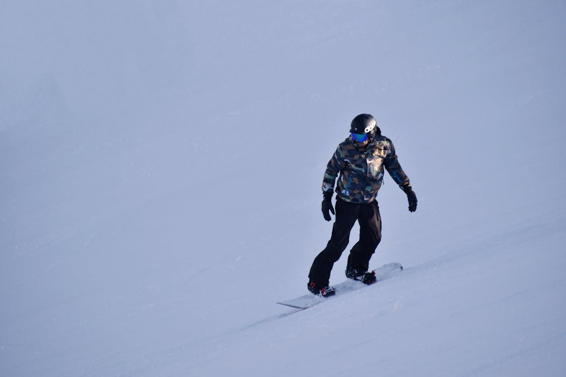 Photo of Person Snowboarding on Snow Covered Field