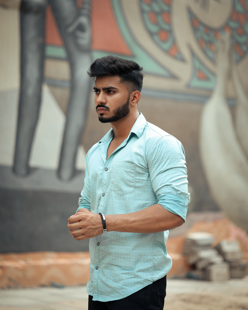 Free Portrait of a stylish young man posing outdoors with a mural backdrop. Stock Photo