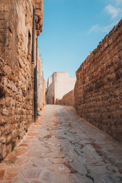Free Explore the narrow, sunlit stone alleyways of historic Mardin, Türkiye on a clear day. Stock Photo