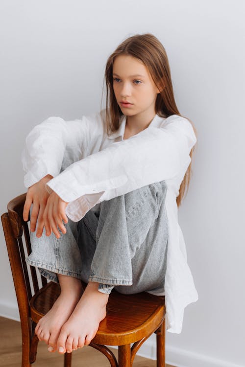 A Barefoot Teenage Girl Sitting on a Chair · Free Stock Photo