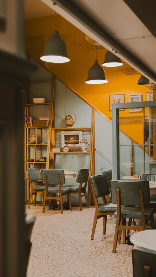 Free Inviting vintage cafe interior with soft lighting, art, and cozy seating. Perfect for a relaxed ambiance. Stock Photo