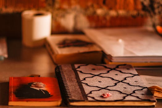 A cozy workspace setup with notebooks, books, and warm lighting, perfect for study or creative work.