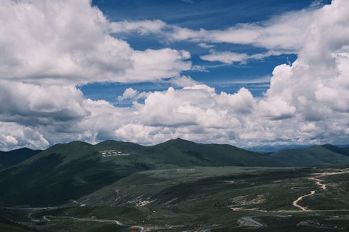 Free Breathtaking aerial landscape of green hills under a sky full of white fluffy clouds. Stock Photo