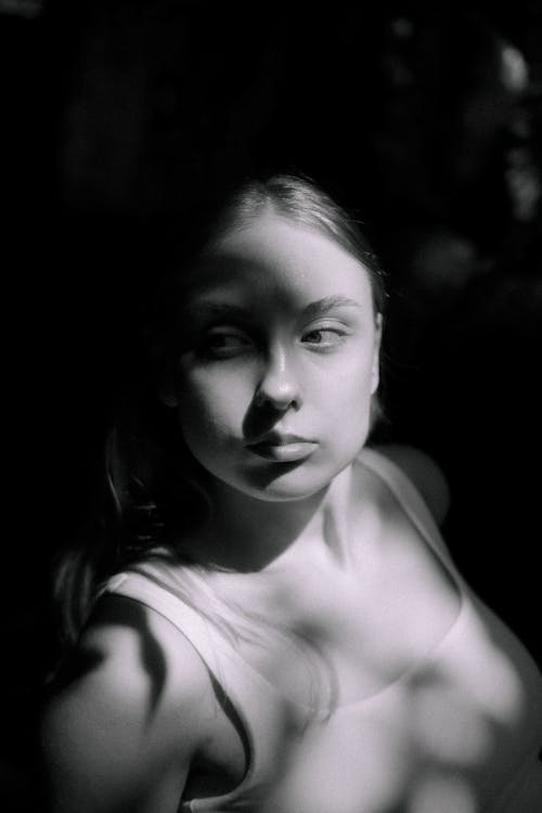 Black and White Photo of a Young Woman Standing in Sunlight 
