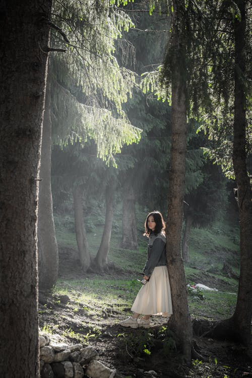 Young Woman in a Dress Standing in the Forest 