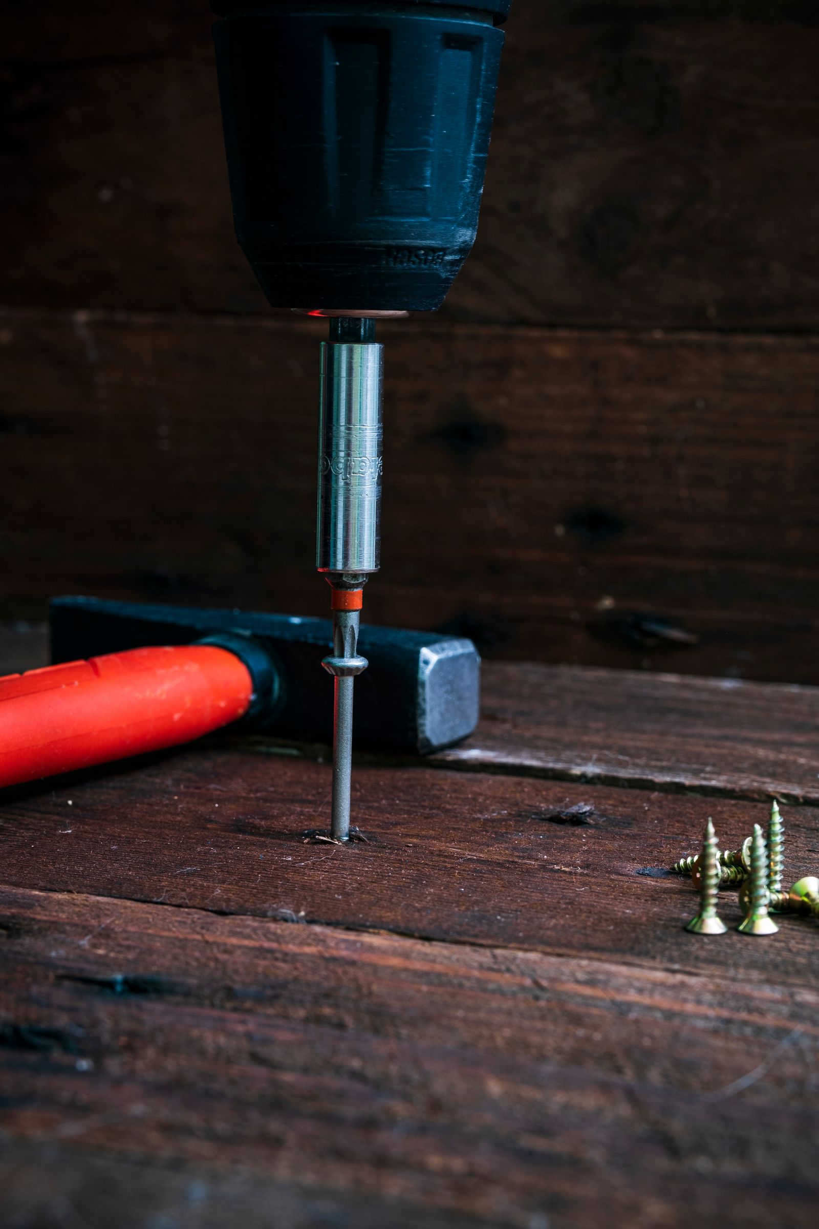 Cordless drill driving a screw into a timber board