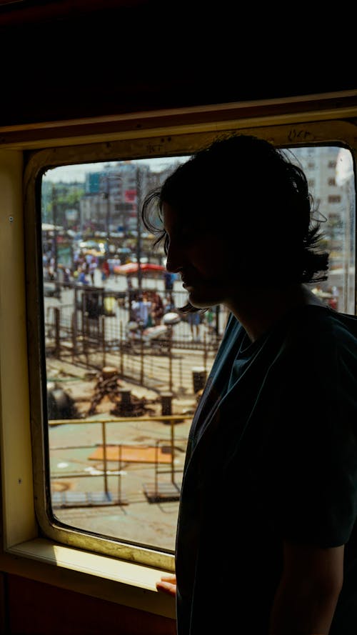 Man Standing by Window in Public Transportation