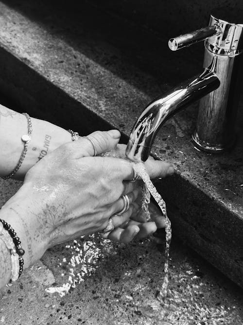 Person Washing Hands under a Faucet